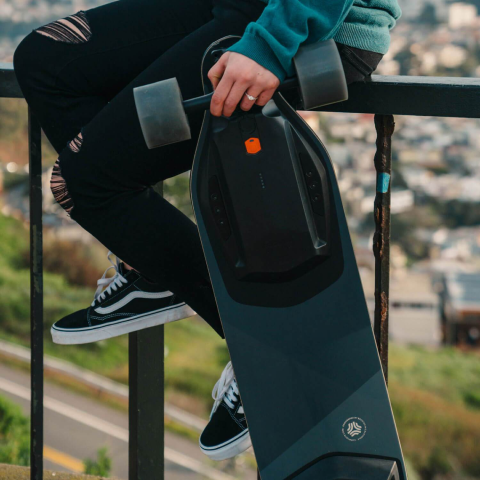 one holding a sketboard sitting on a fence